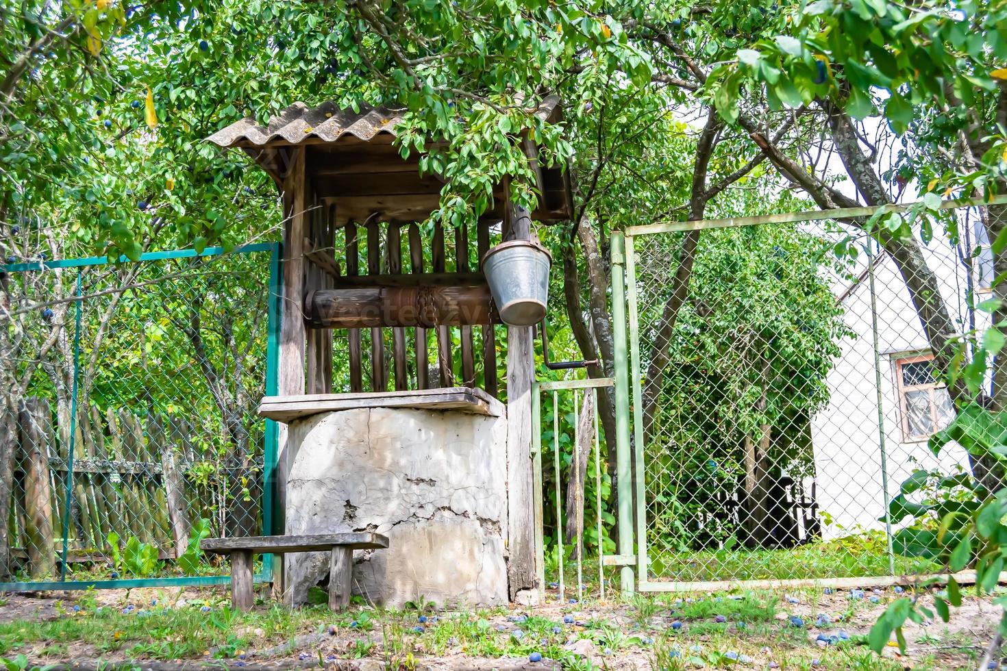 Old well with iron bucket on long forged chain for clean drinking water photo