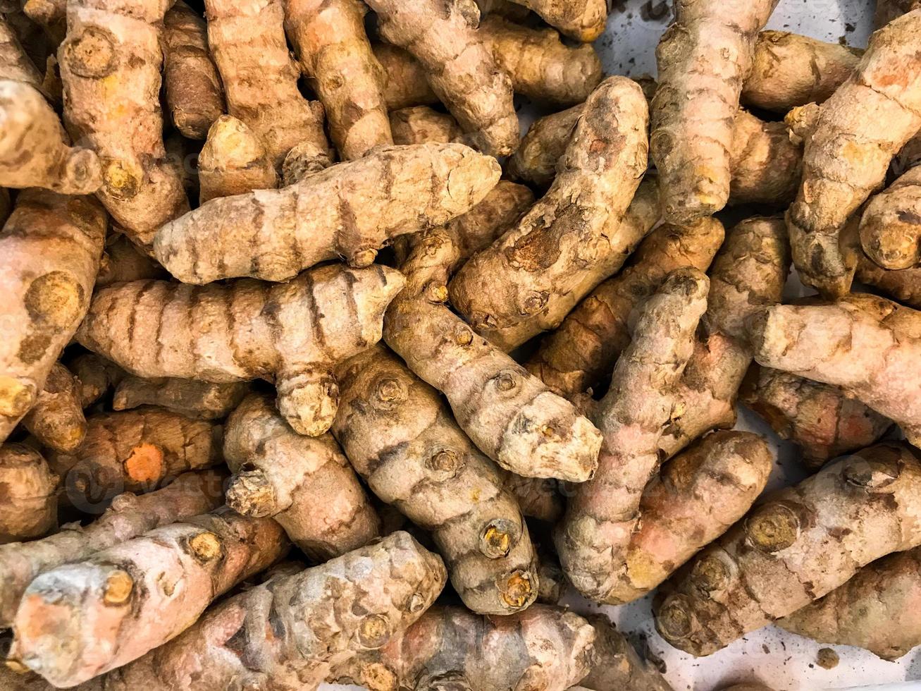 Pile of Fresh Kunyit Indonesian Spelling or Turmeric Curcuma Longa of the ginger family on sale in market photo