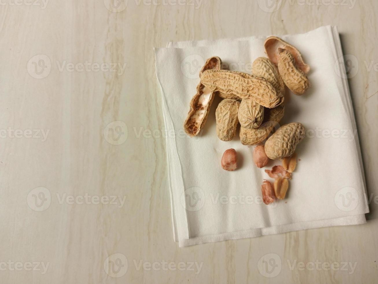 Up view of peanuts on a textured table, peanut shells photo