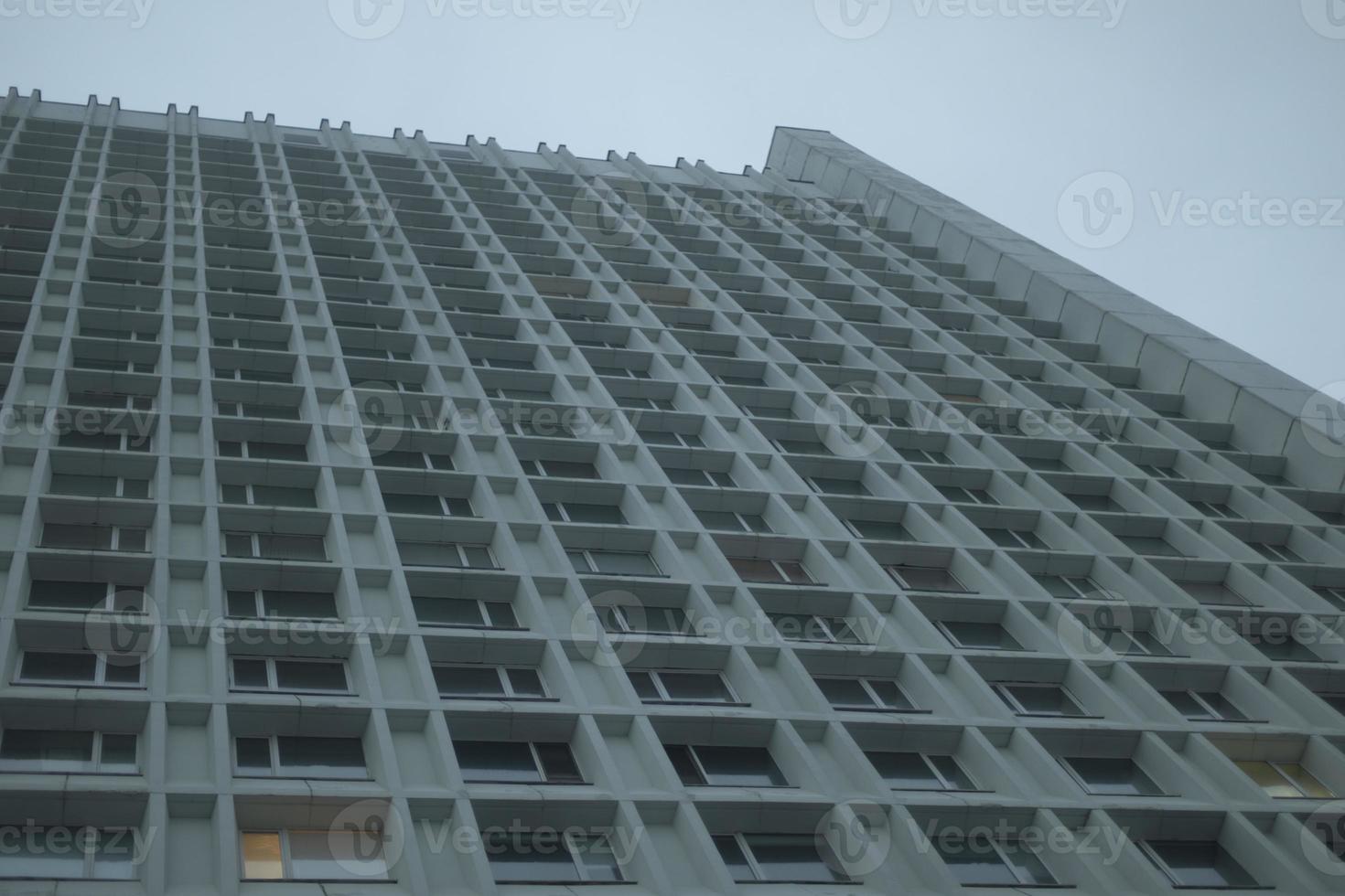 Lots of windows in skyscraper. High-rise building in city. Offices on grey day. photo