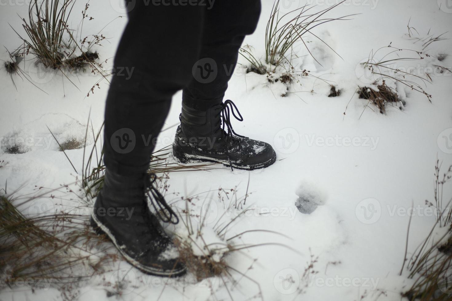 Black boots in winter. Girl in men's shoes. Snow shoes black clothes. photo