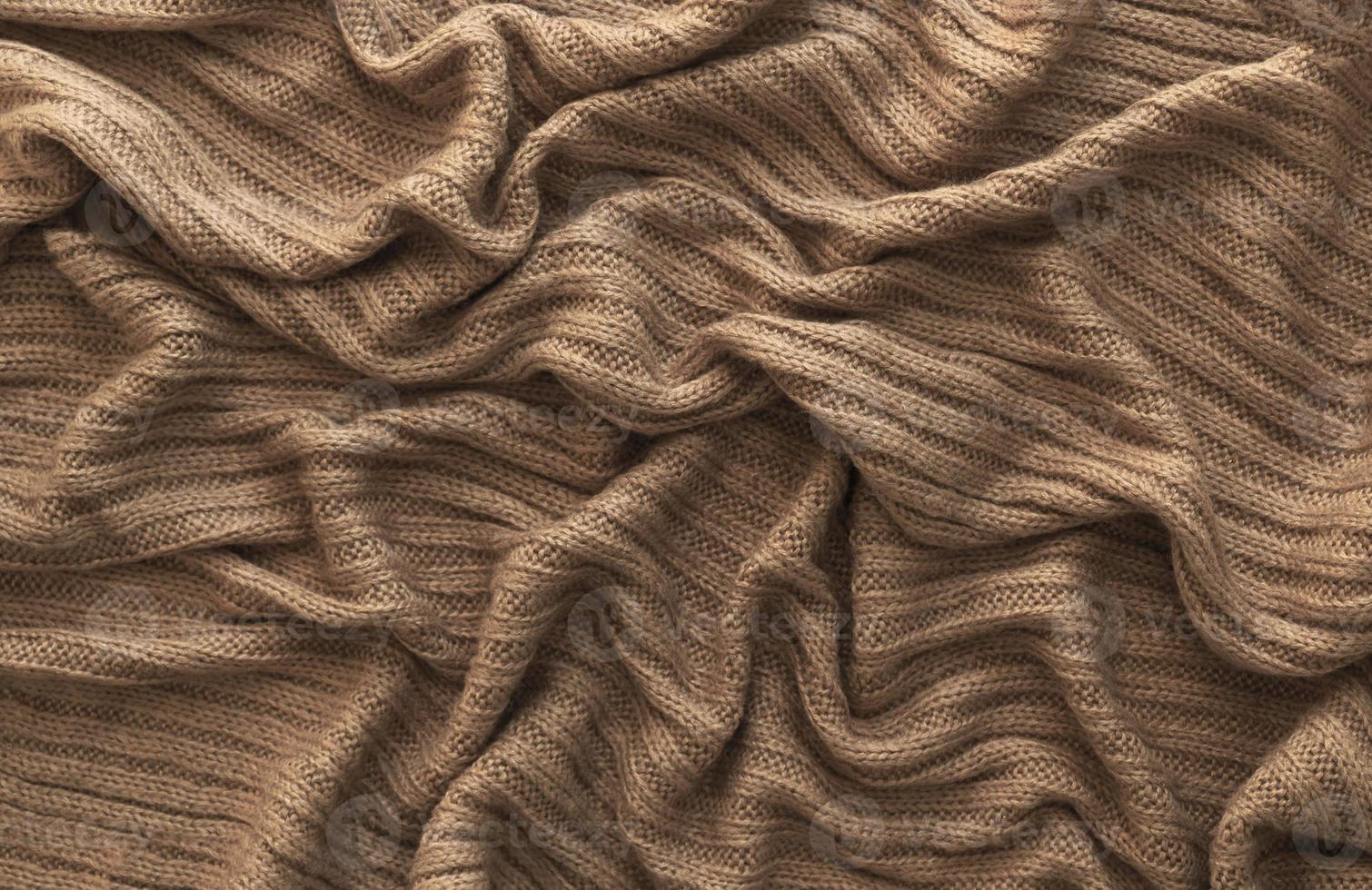 Brown crumpled knitted scarf or sweater texture, top view. Texture background of warm crocheted clothing textile. Knitwear fabric. photo