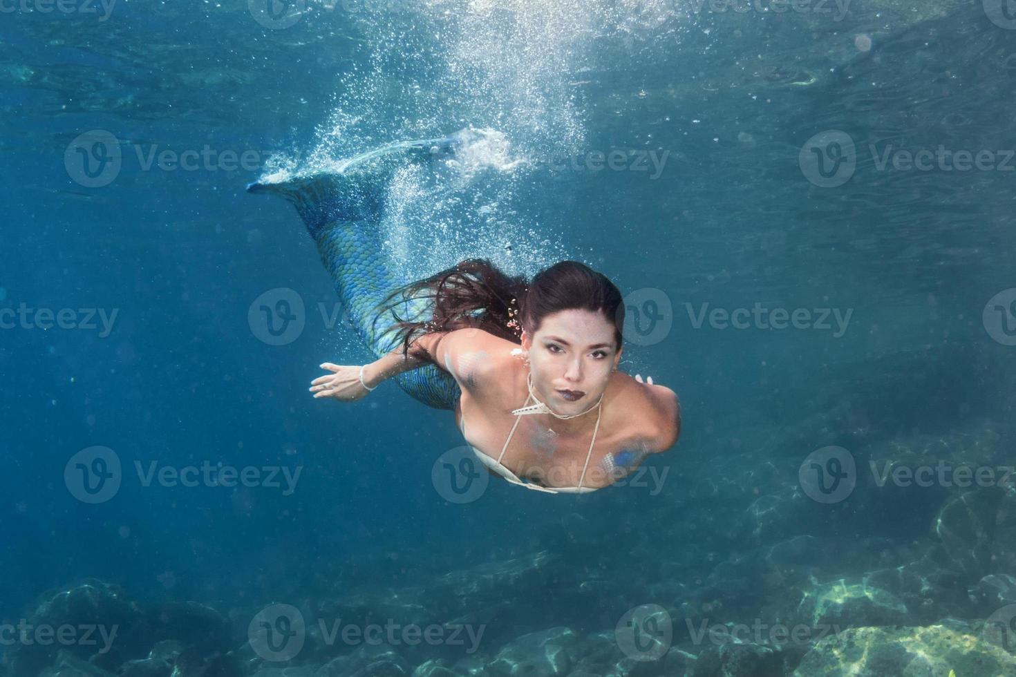 Mermaid swimming underwater in the deep blue sea photo