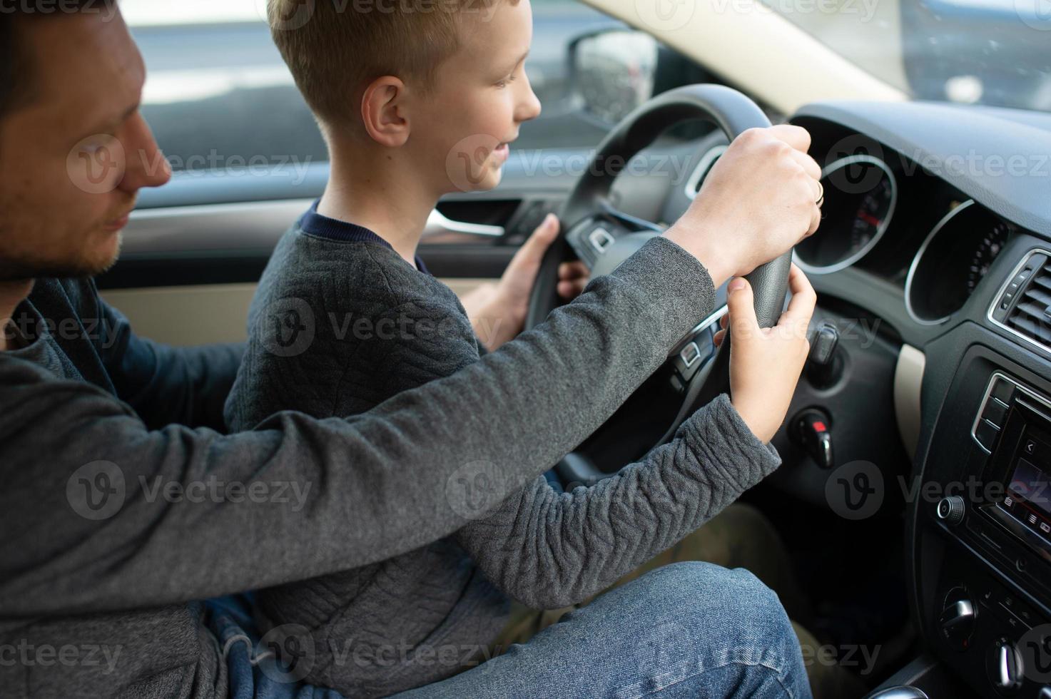 Dad shows his little son how to drive a car photo