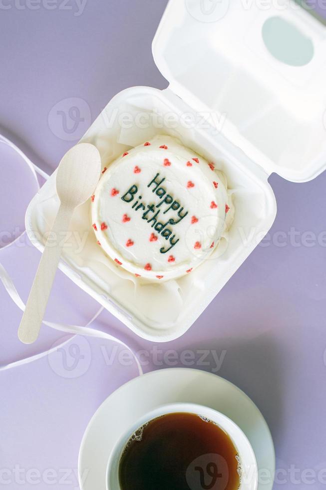 An open box with a birthday bento cake on a purple background photo