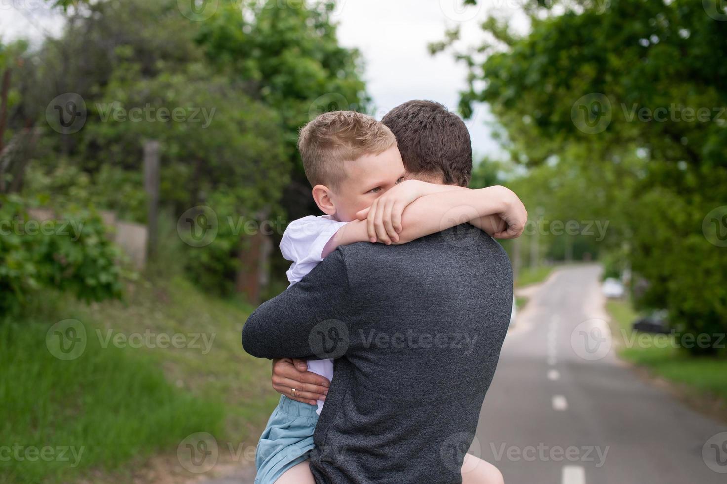 Cute son hugs dad by the neck and cries photo