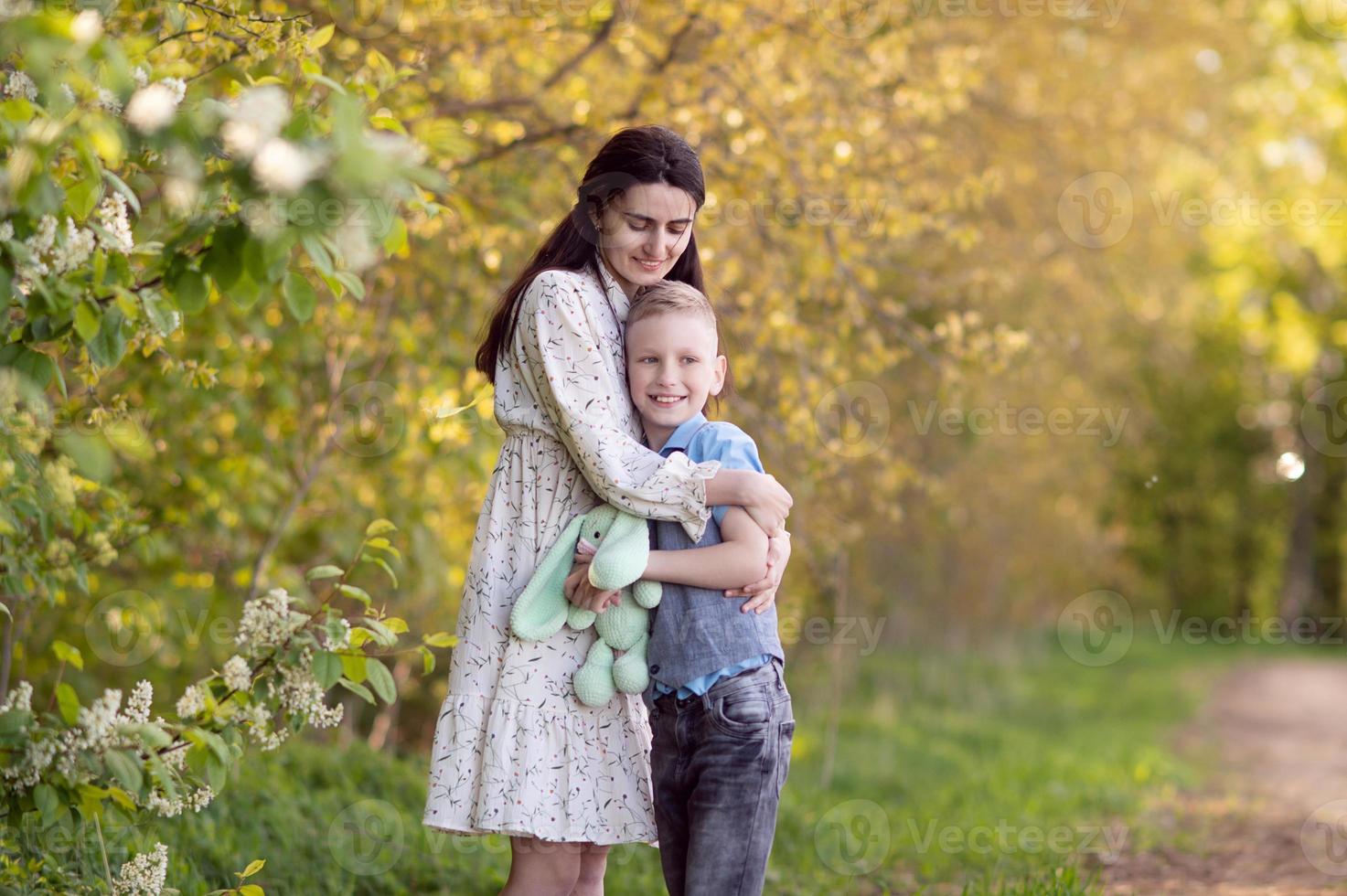 mamá con oscuro pelo abrazos su hijo y mira a él foto