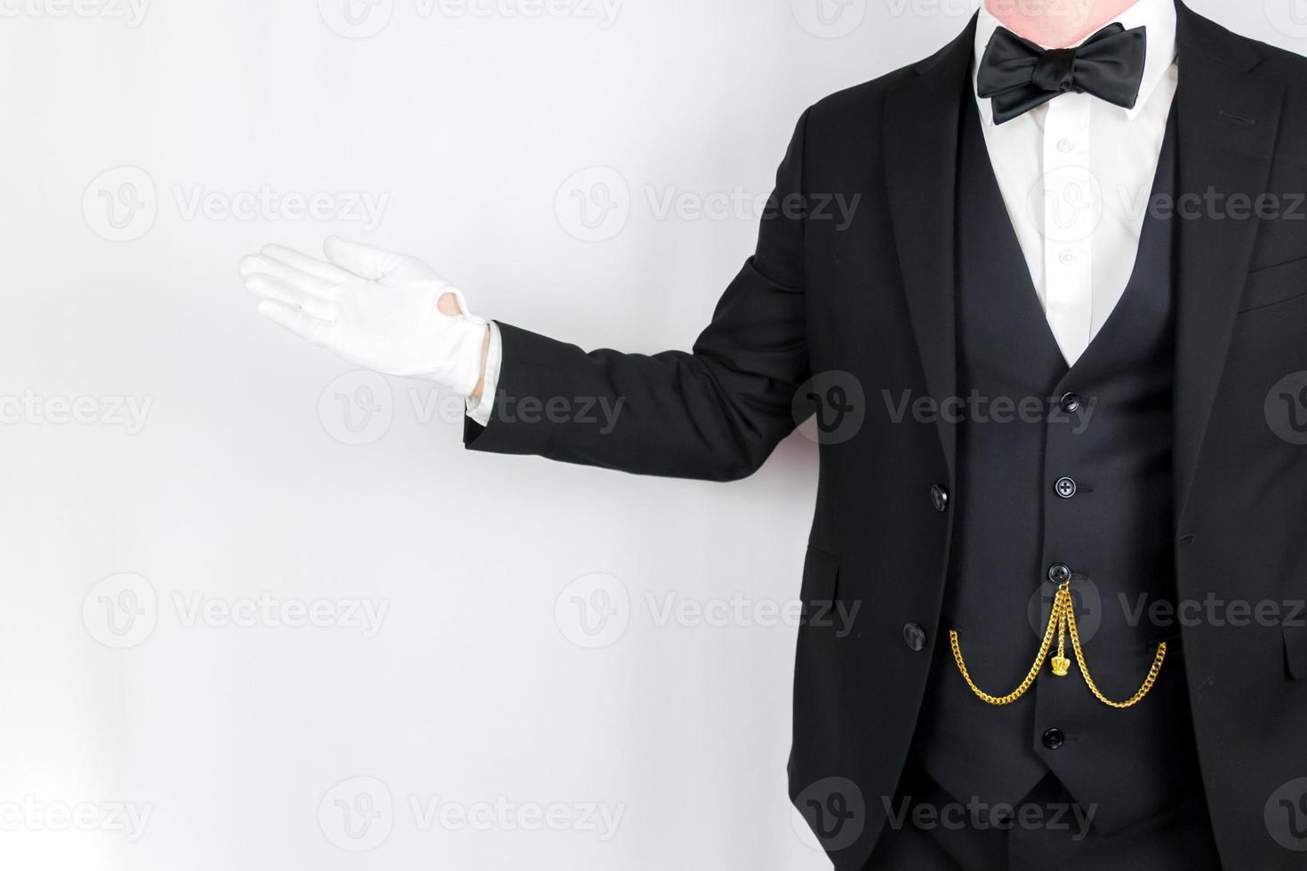 Portrait of Butler in Dark Suit and White Gloves Standing With Welcoming Gesture. Concept of Service Industry and Professional Hospitality. photo