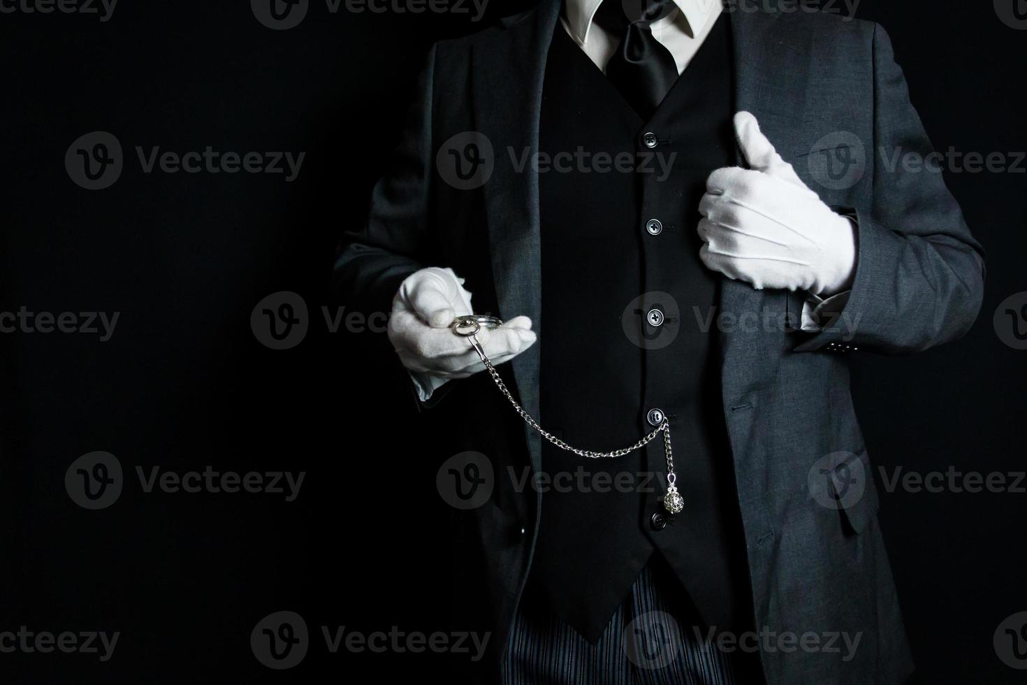 Portrait of Butler or Servant in Dark Suit and White Gloves on Black Background Holding Pocket Watch. Copy Space for Service Industry and Professional Hospitality. photo