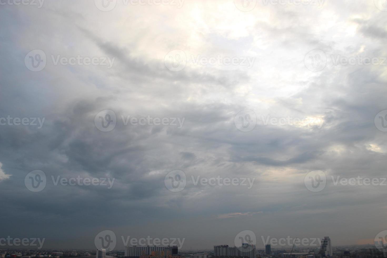 sunset sky above heavy dark clouds almost raining with dramatic Rays of light shining down background and city evening time photo