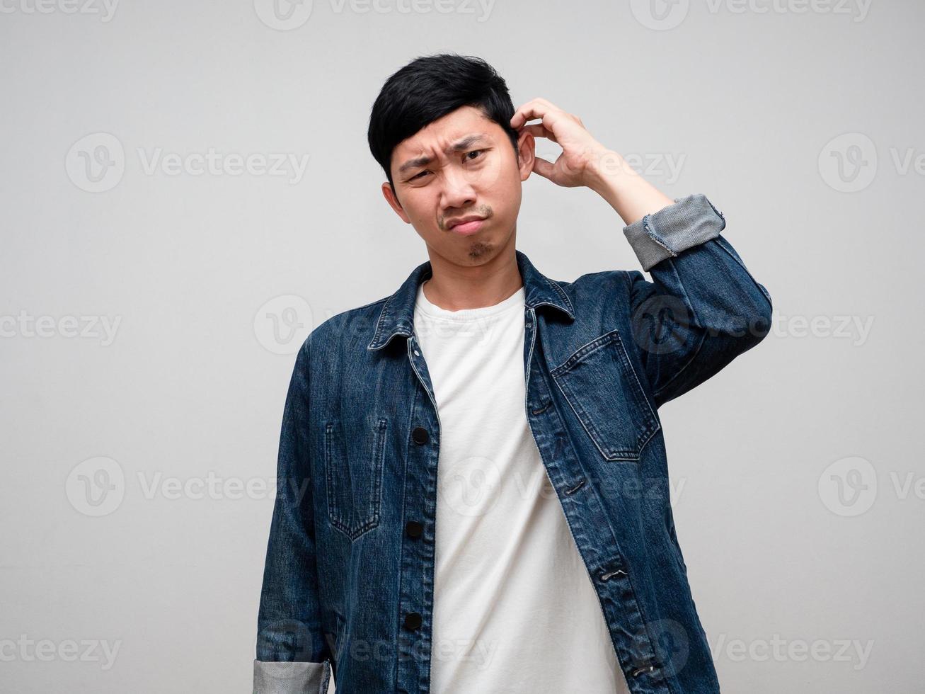 joven hombre pantalones camisa rasguño cabeza siente duda y confuso aislado foto