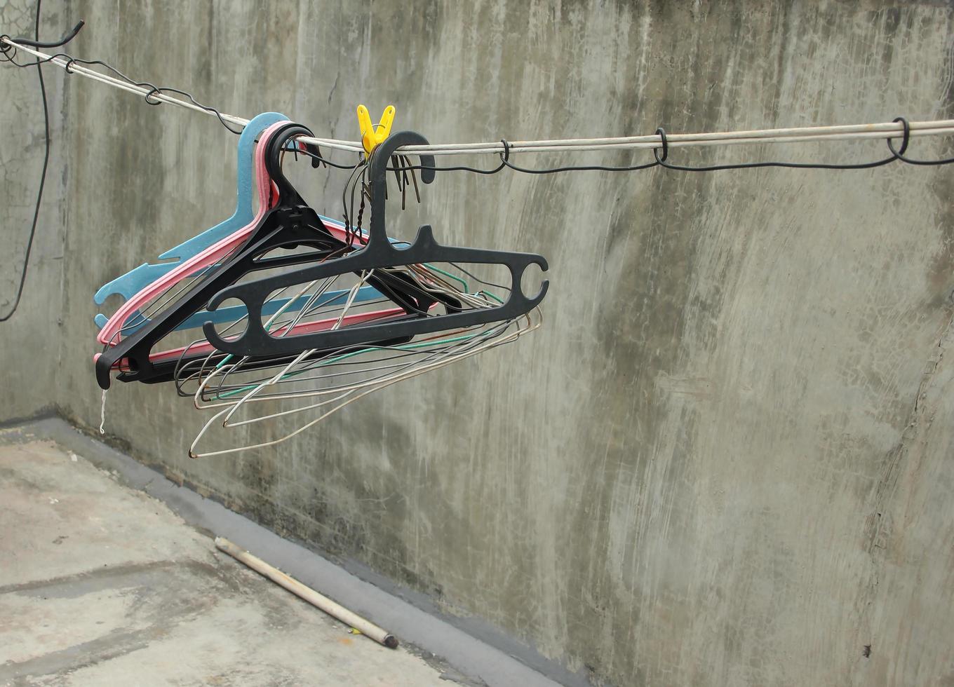 Multiple black, blue, white, and pink clothes hanger on simple thread rope clothes line isolated photo on gray concrete walls and flooring at roof top.