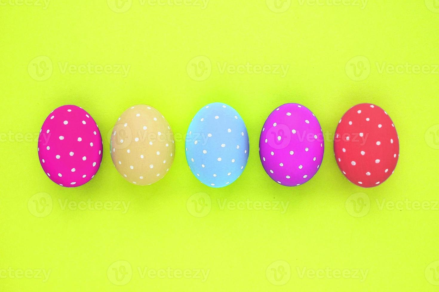 Easter coloured eggs with polka dot on neon yellow background. Flatlay postcard creative concept. Isolated decorated card, poster, banner, web, magazine. Minimal idea with copy space, close up spring photo