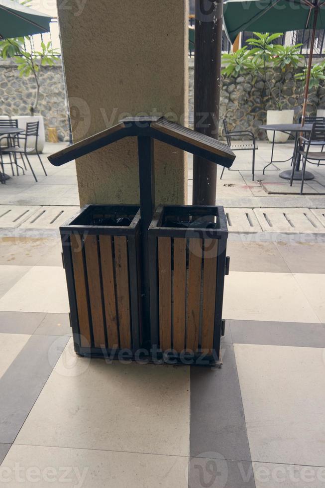 Single rubbish bin, garbage and waste bin made of wooden material. A garbage collection tank in the corner of building. A clean container for household waste.  Wooden waste boxes or trash bin. photo