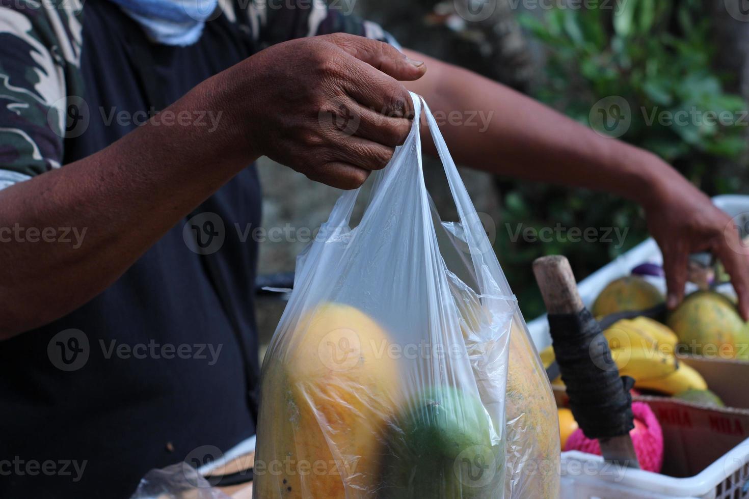 A peddler trader holding papaya plastic that has been weighed in Indonesia photo