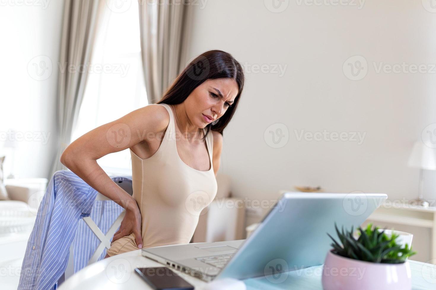 Business Woman suffering from back pain. Incorrect sitting posture problems. Pain relief , chiropractic concept. Beautiful young woman suffering from backache in office photo