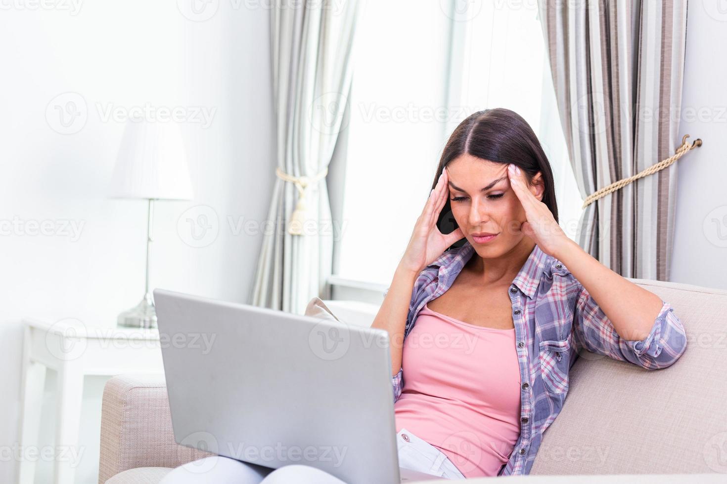 cansado mujer masajear templos, sufrimiento desde dolor de cabeza después computadora trabajar, sentado con ordenador portátil a hogar, agotado joven hembra con cerrado ojos conmovedor cabeza, alivio dolor, migraña foto