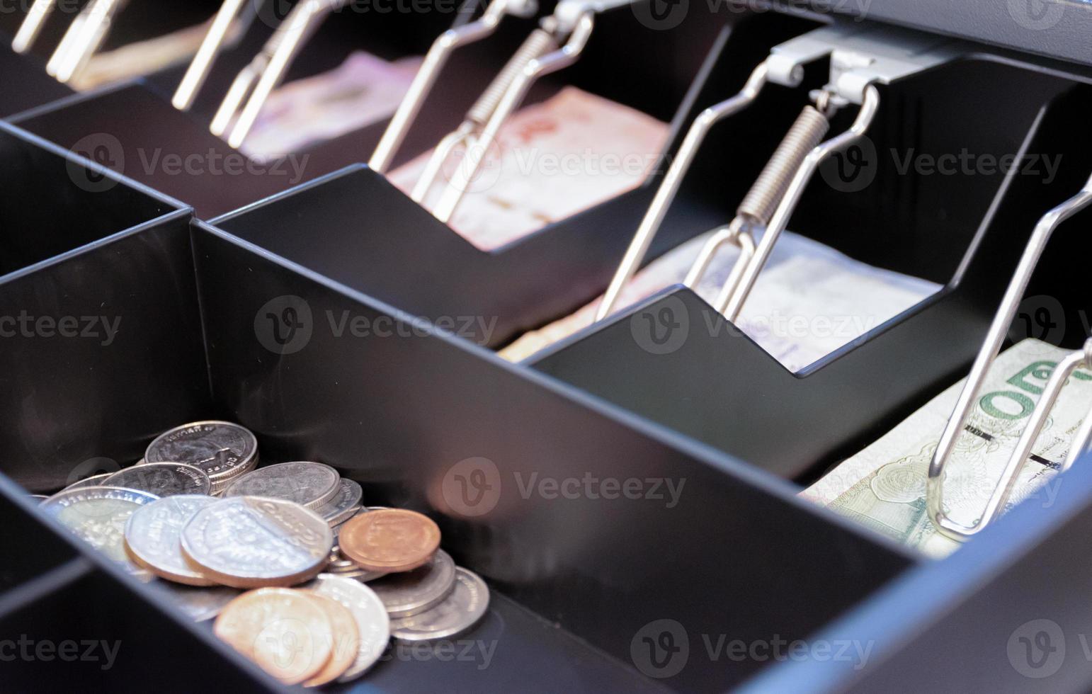 Thai bank notes and coins are in the cashier machine photo