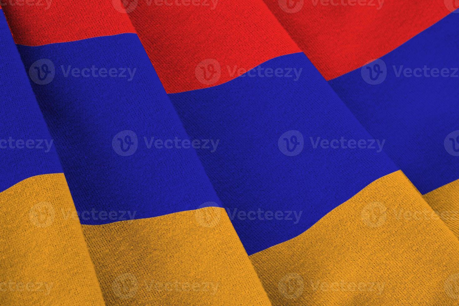 Armenia flag with big folds waving close up under the studio light indoors. The official symbols and colors in banner photo