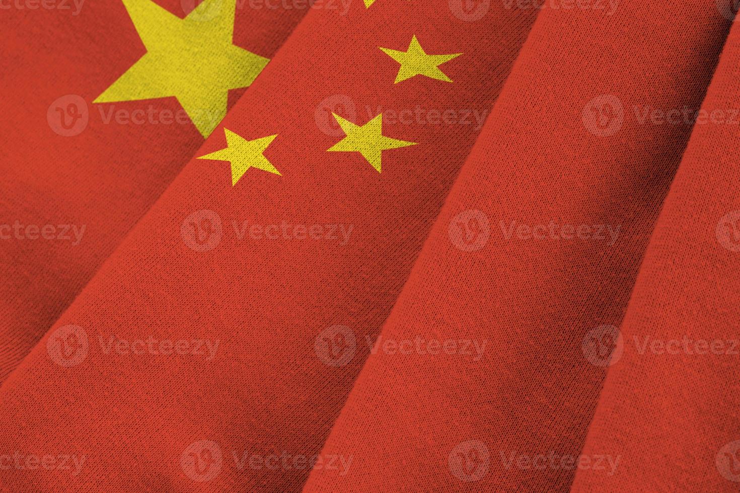 China flag with big folds waving close up under the studio light indoors. The official symbols and colors in banner photo