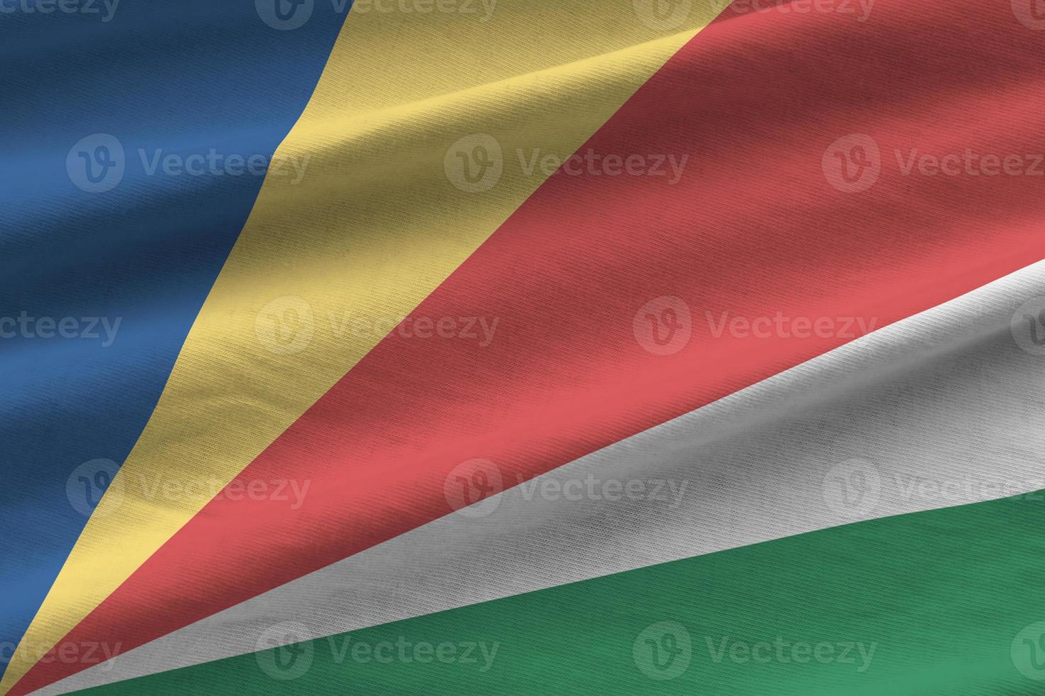 Seychelles flag with big folds waving close up under the studio light indoors. The official symbols and colors in banner photo