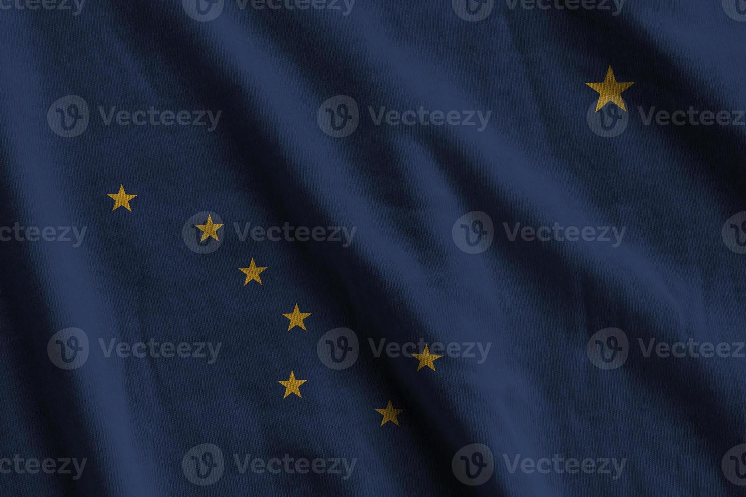 Alaska US state flag with big folds waving close up under the studio light indoors. The official symbols and colors in banner photo