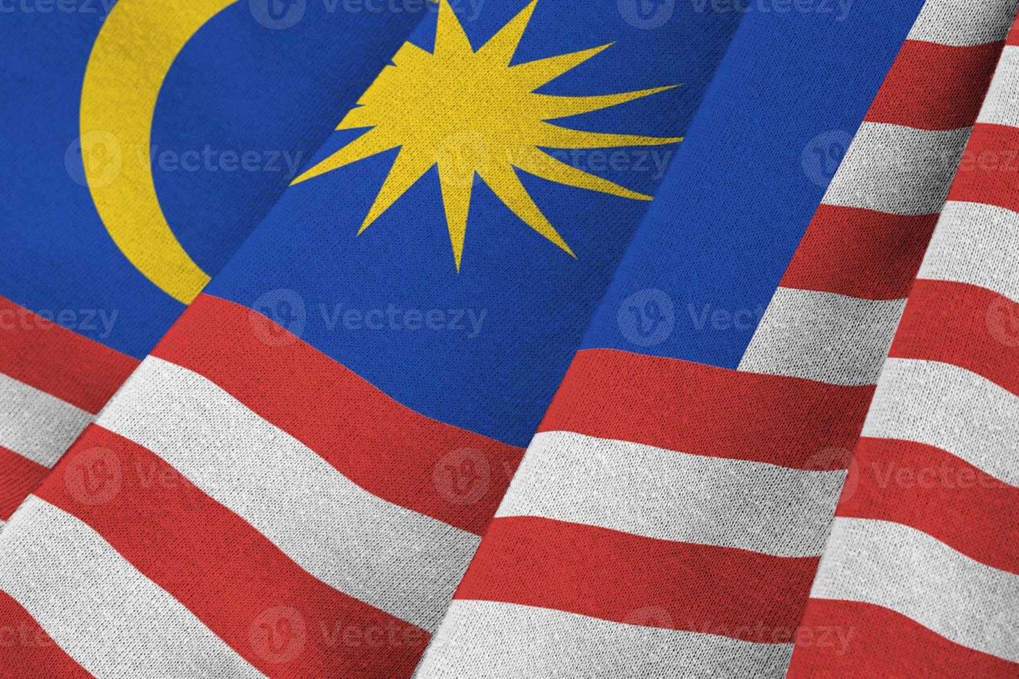 Malaysia flag with big folds waving close up under the studio light indoors. The official symbols and colors in banner photo