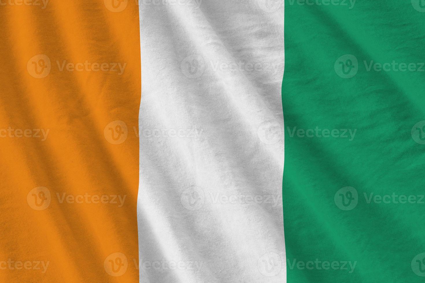 Ivory Coast flag with big folds waving close up under the studio light indoors. The official symbols and colors in banner photo