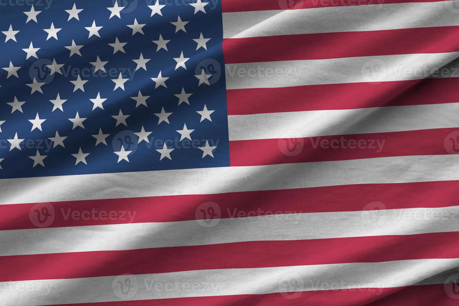 United States of America flag with big folds waving close up under the studio light indoors. The official symbols and colors in banner photo