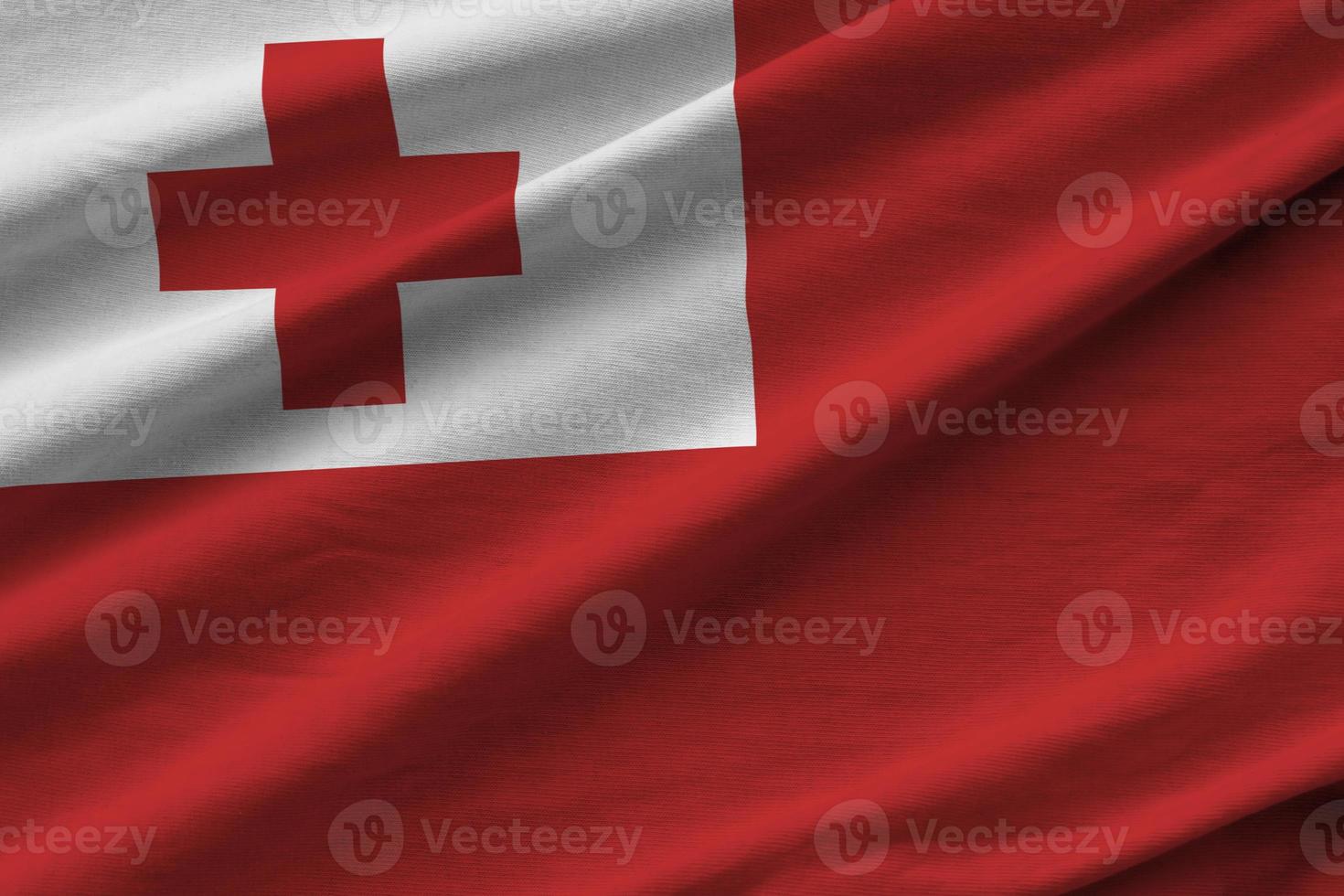 Tonga flag with big folds waving close up under the studio light indoors. The official symbols and colors in banner photo