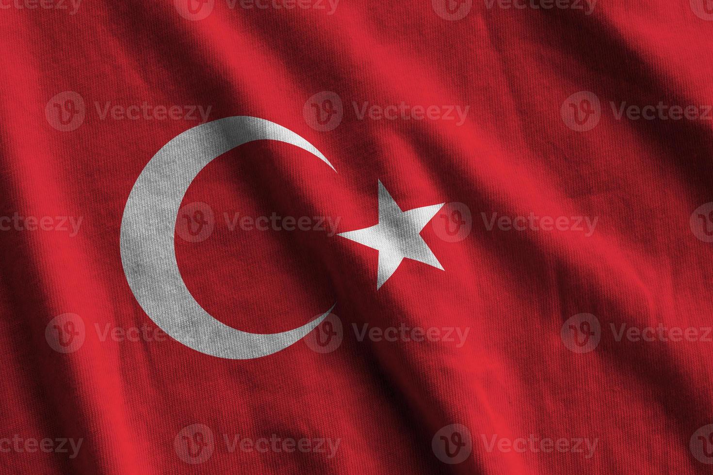 Turkey flag with big folds waving close up under the studio light indoors. The official symbols and colors in banner photo