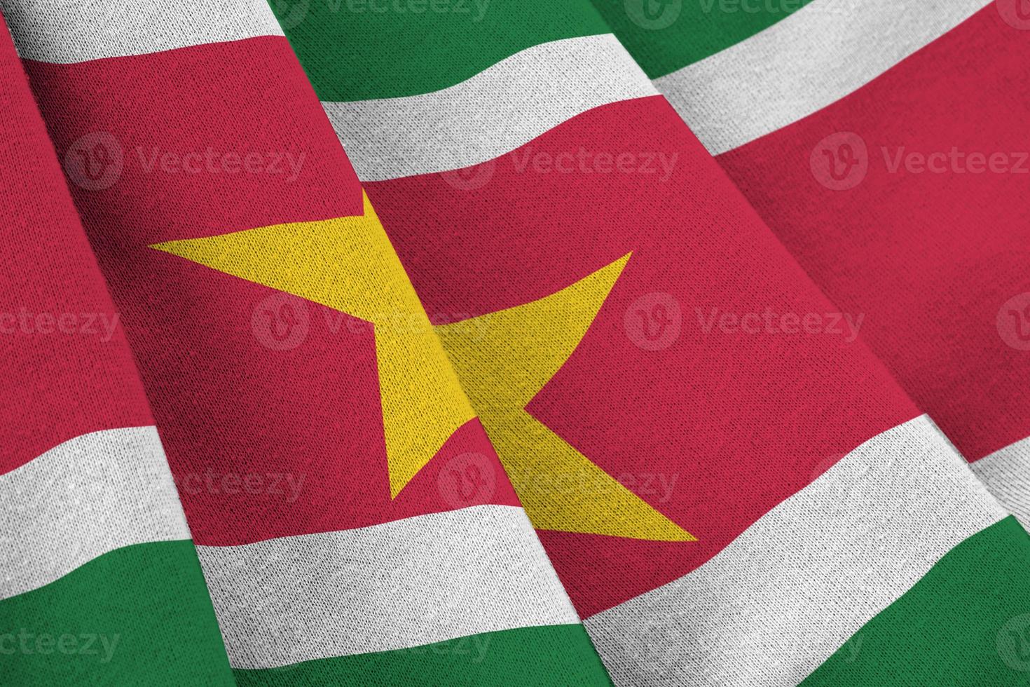 Suriname flag with big folds waving close up under the studio light indoors. The official symbols and colors in banner photo