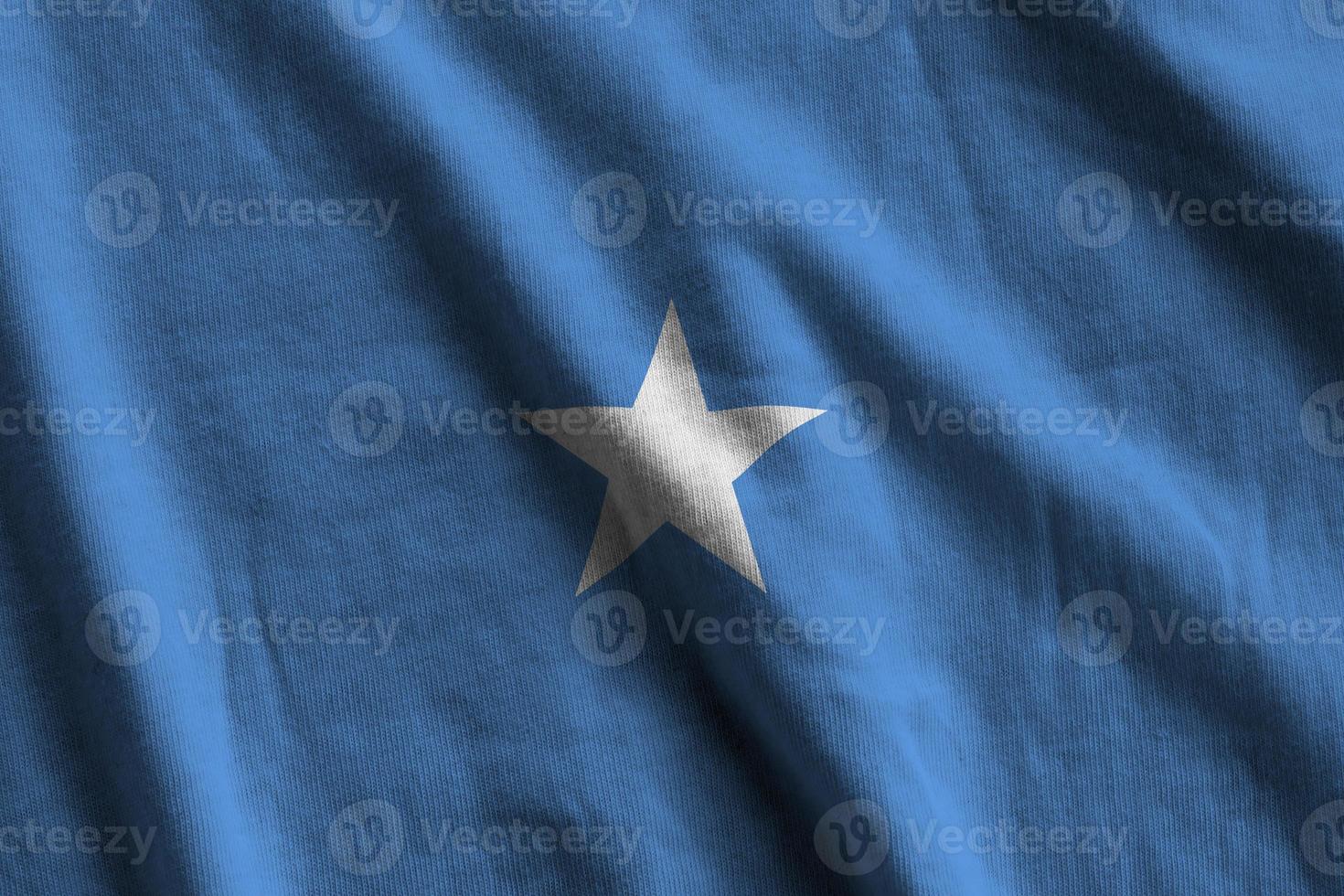 Somalia flag with big folds waving close up under the studio light indoors. The official symbols and colors in banner photo