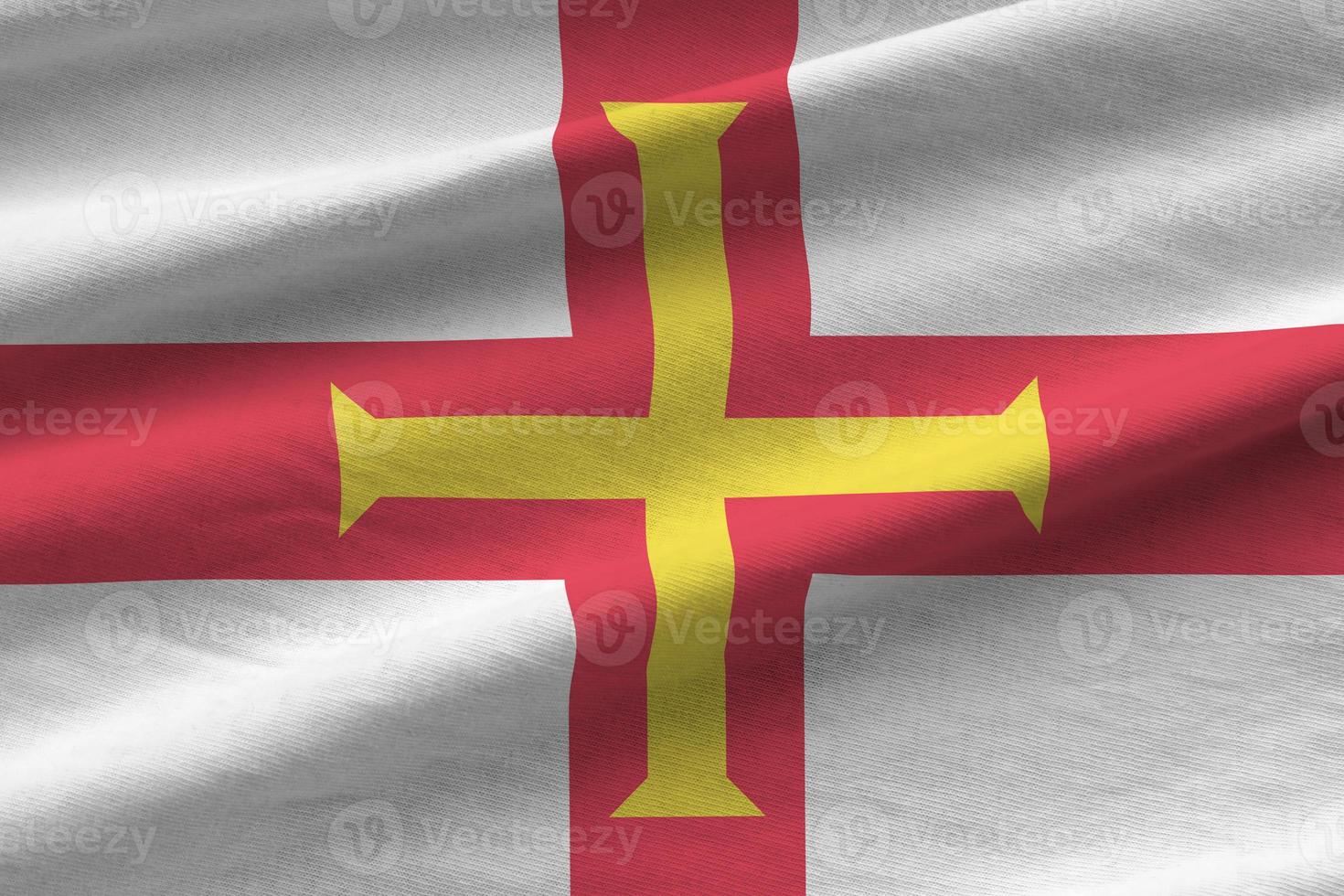 Guernsey flag with big folds waving close up under the studio light indoors. The official symbols and colors in banner photo