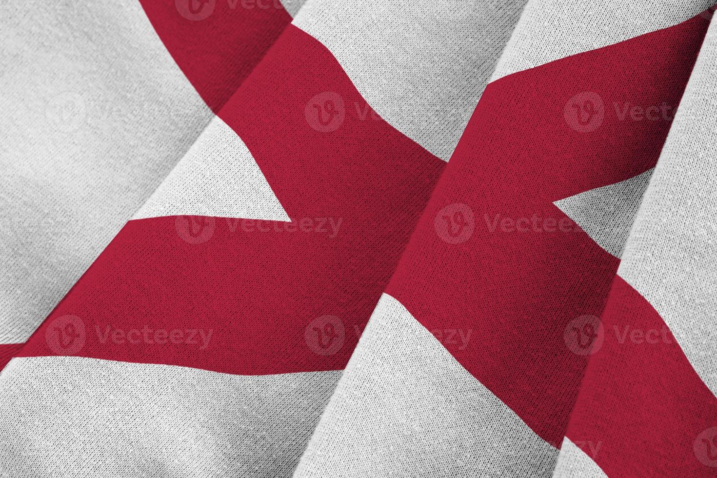 Alabama US state flag with big folds waving close up under the studio light indoors. The official symbols and colors in banner photo