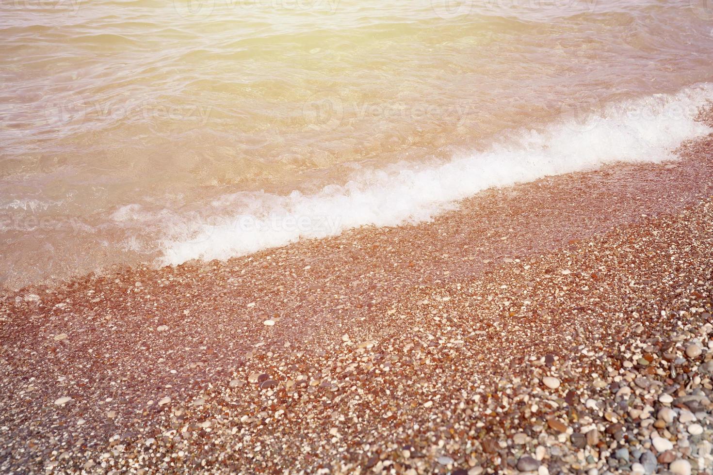 Bank of pebbles with the sea and beach in the background photo