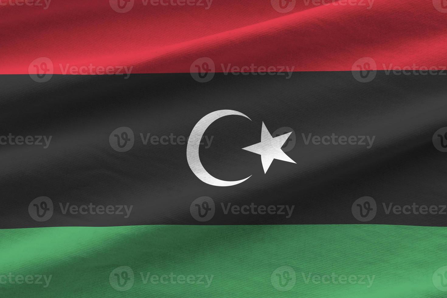 Libya flag with big folds waving close up under the studio light indoors. The official symbols and colors in banner photo