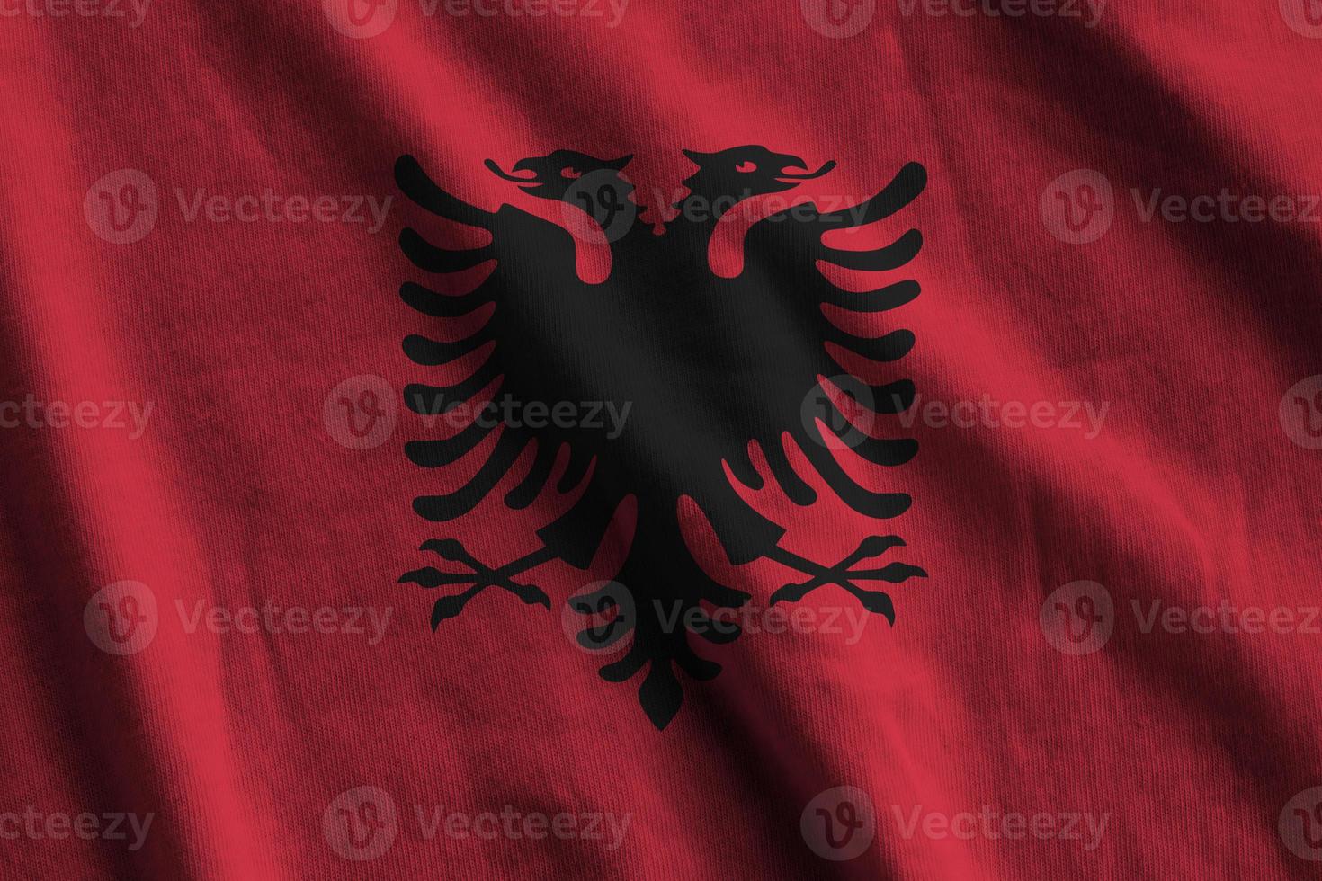Albania flag with big folds waving close up under the studio light indoors. The official symbols and colors in banner photo