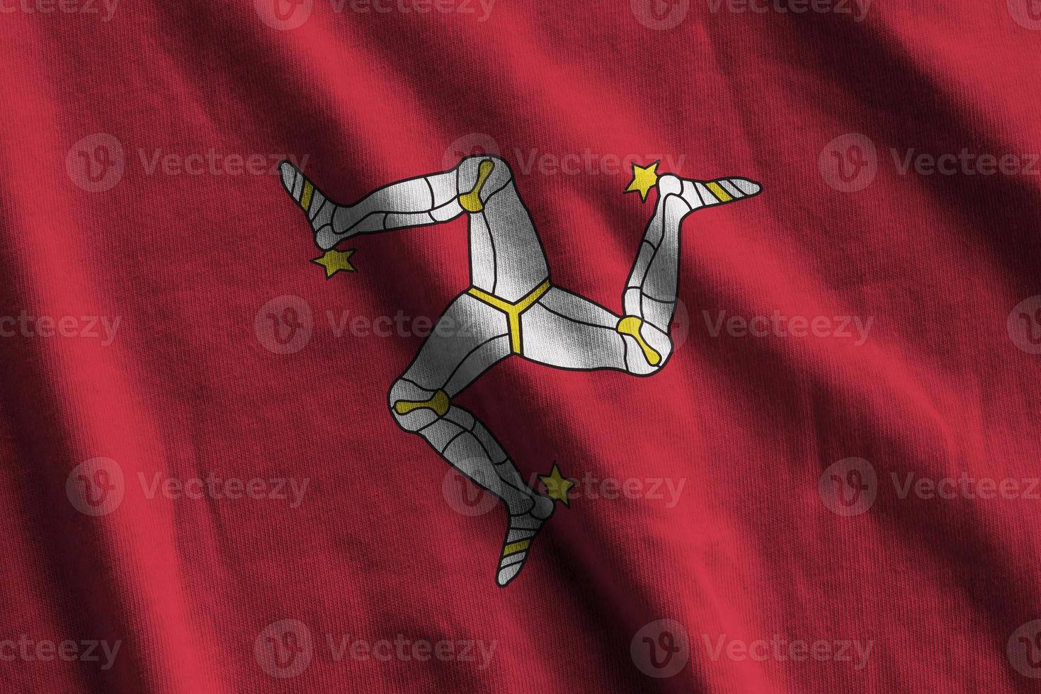 Isle of Man flag with big folds waving close up under the studio light indoors. The official symbols and colors in banner photo