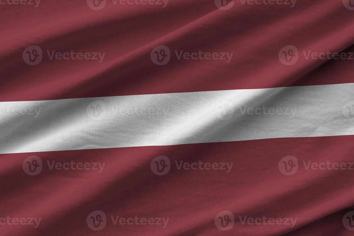 bandera de letonia con grandes pliegues ondeando de cerca bajo la luz del estudio en el interior. los símbolos y colores oficiales en banner foto