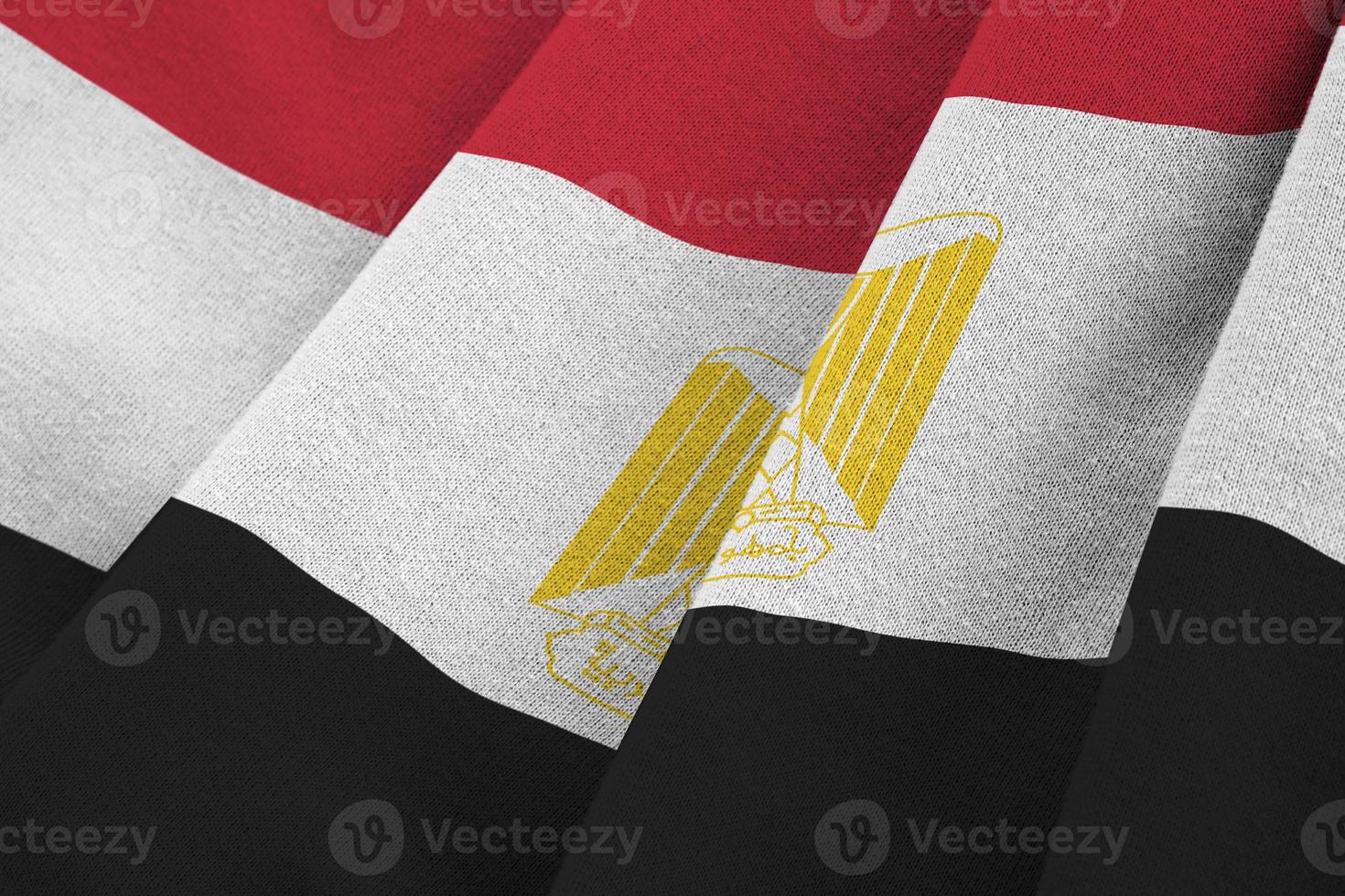 Egypt flag with big folds waving close up under the studio light indoors. The official symbols and colors in banner photo