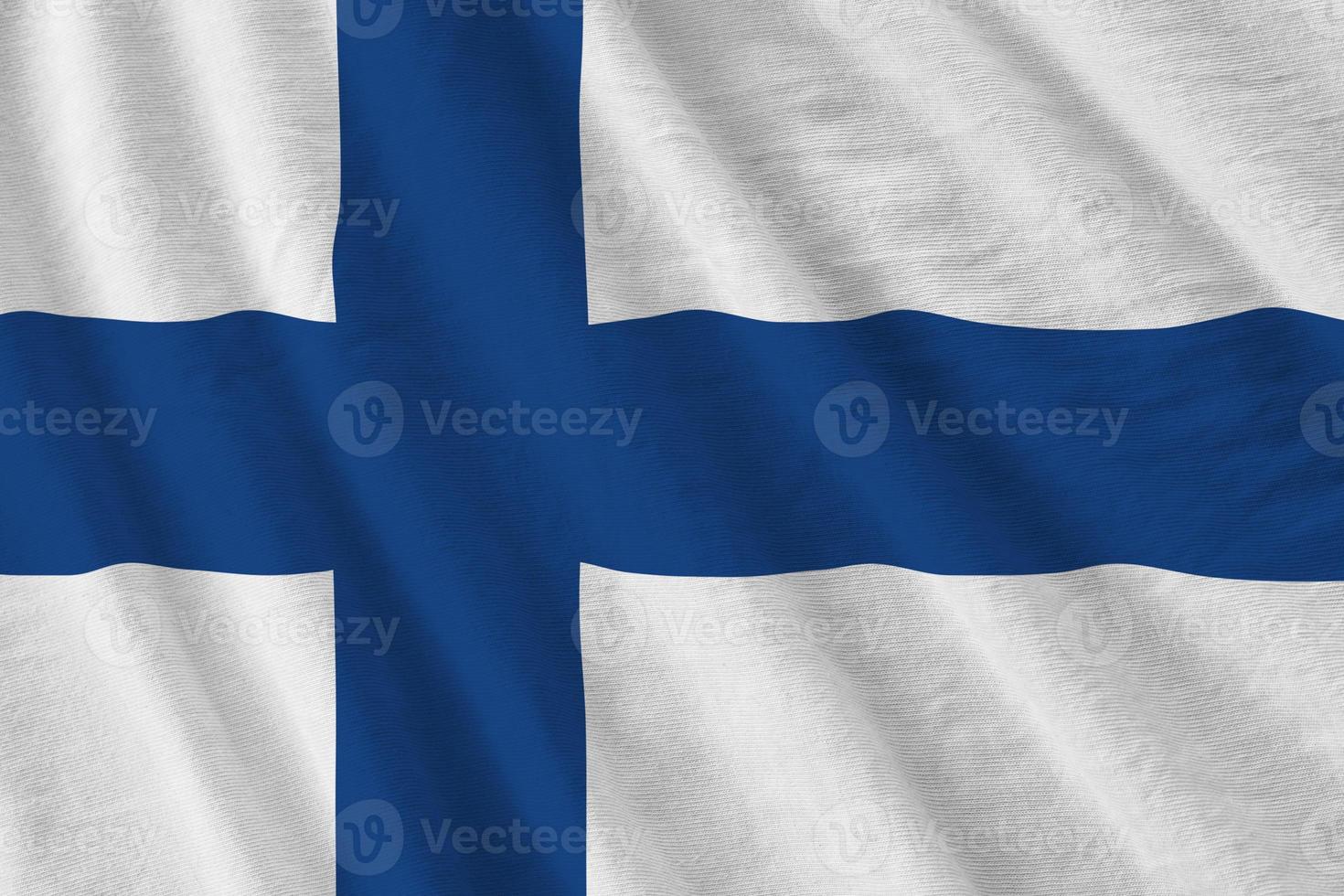 Finland flag with big folds waving close up under the studio light indoors. The official symbols and colors in banner photo