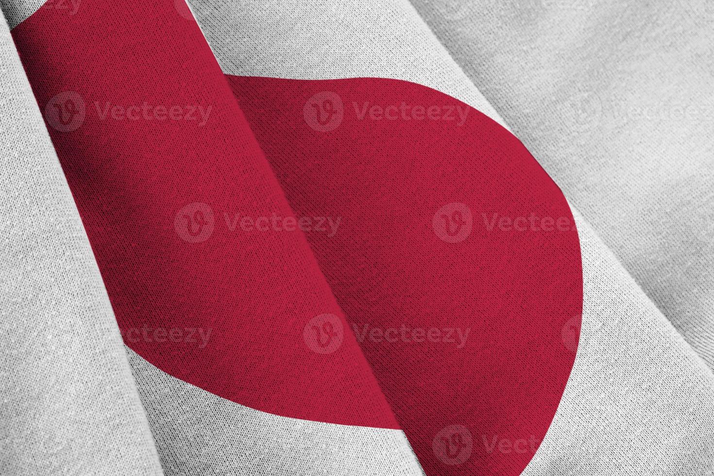 Japan flag with big folds waving close up under the studio light indoors. The official symbols and colors in banner photo