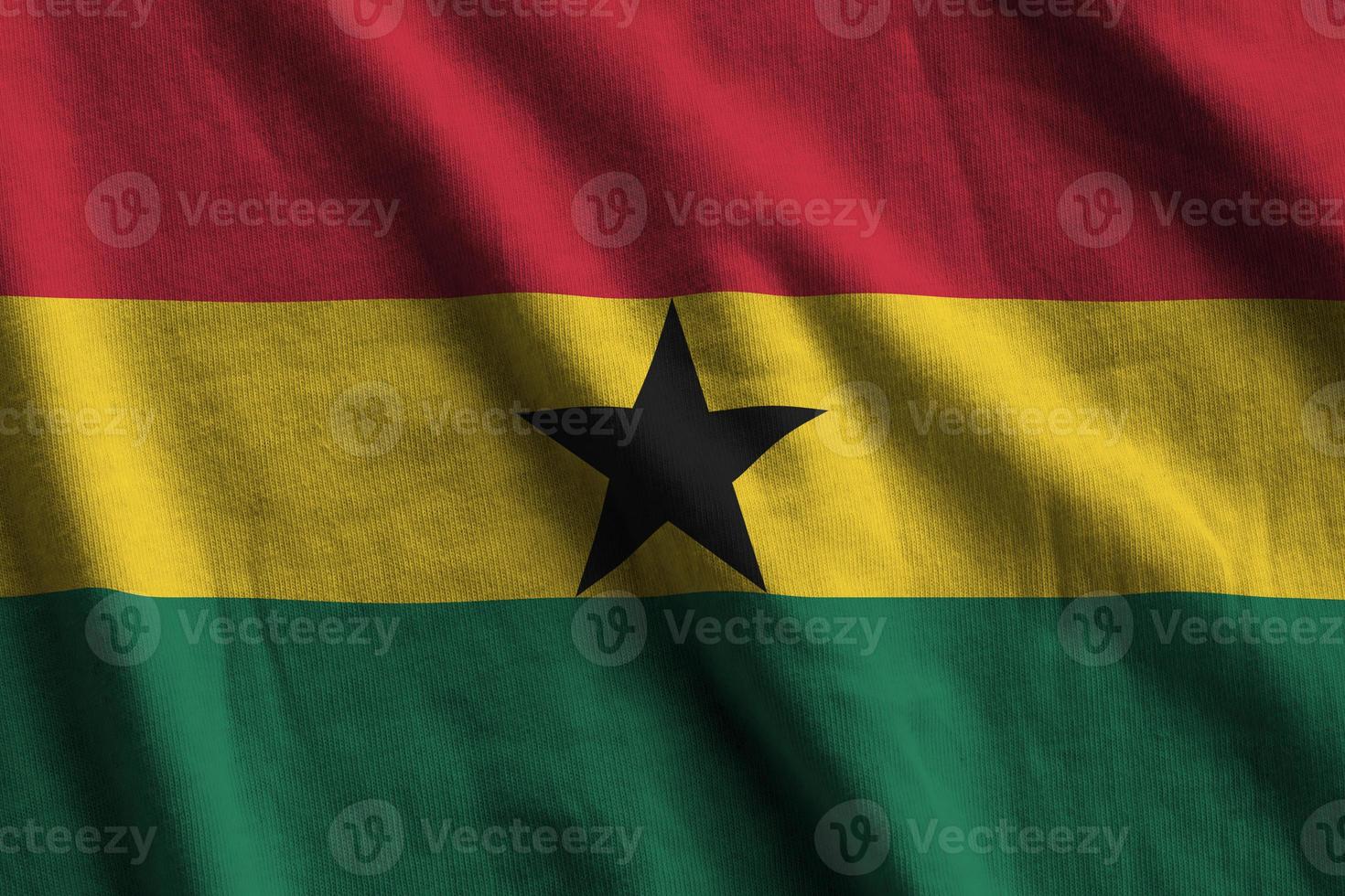 Ghana flag with big folds waving close up under the studio light indoors. The official symbols and colors in banner photo