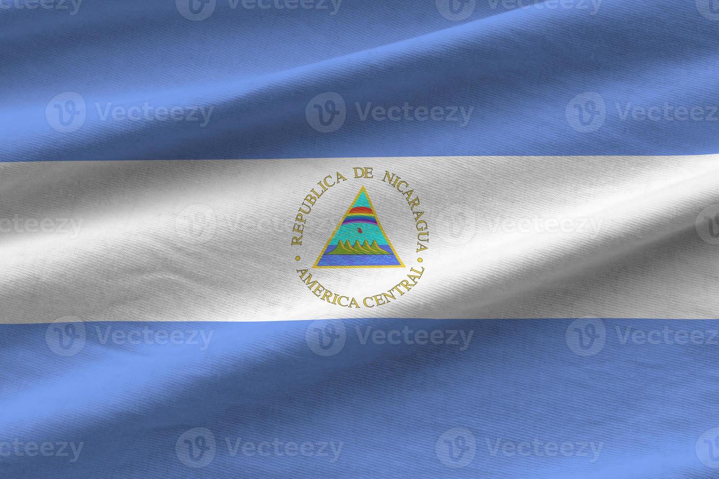 Nicaragua flag with big folds waving close up under the studio light indoors. The official symbols and colors in banner photo