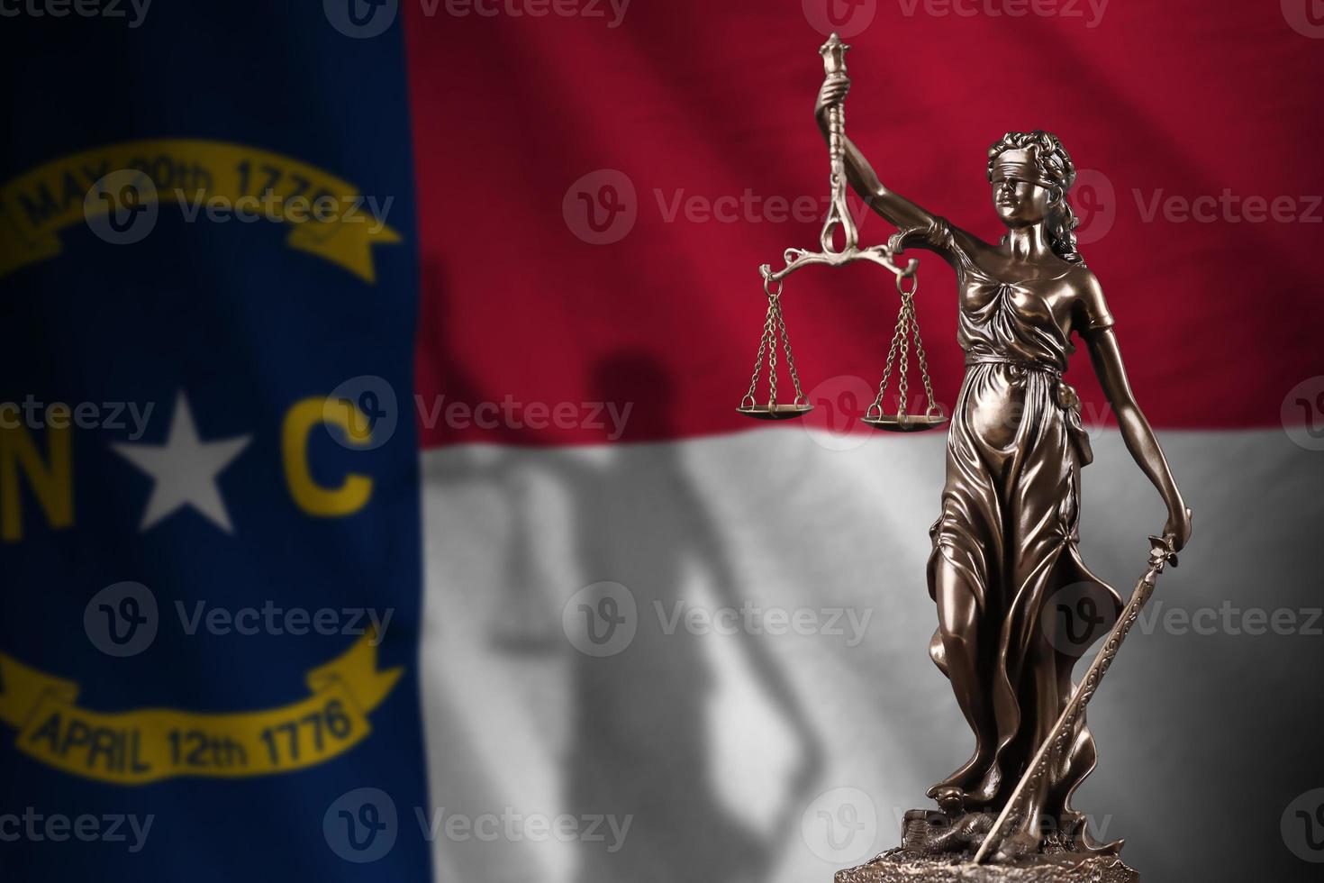 North Carolina US state flag with statue of lady justice and judicial scales in dark room. Concept of judgement and punishment photo