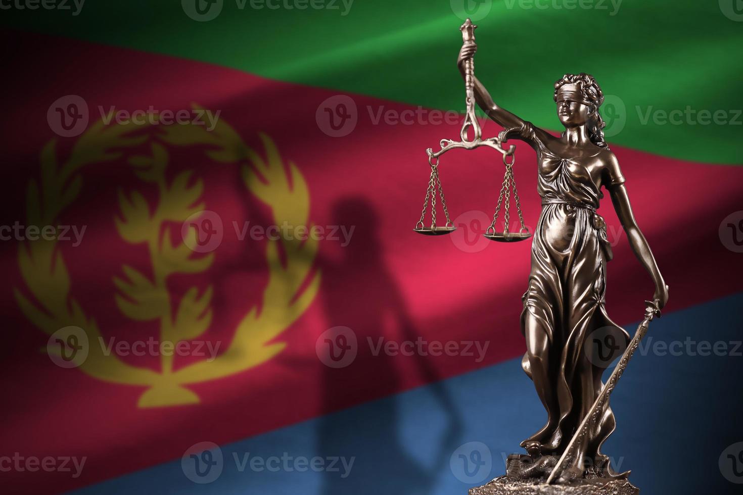 Eritrea flag with statue of lady justice and judicial scales in dark room. Concept of judgement and punishment photo