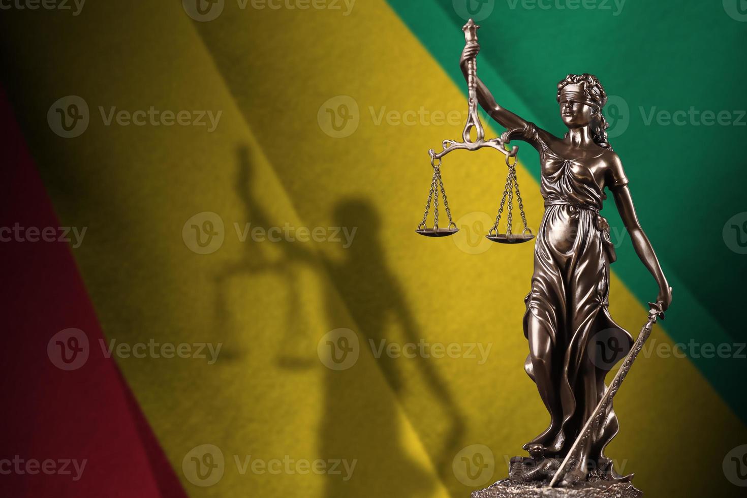 Guinea flag with statue of lady justice and judicial scales in dark room. Concept of judgement and punishment photo