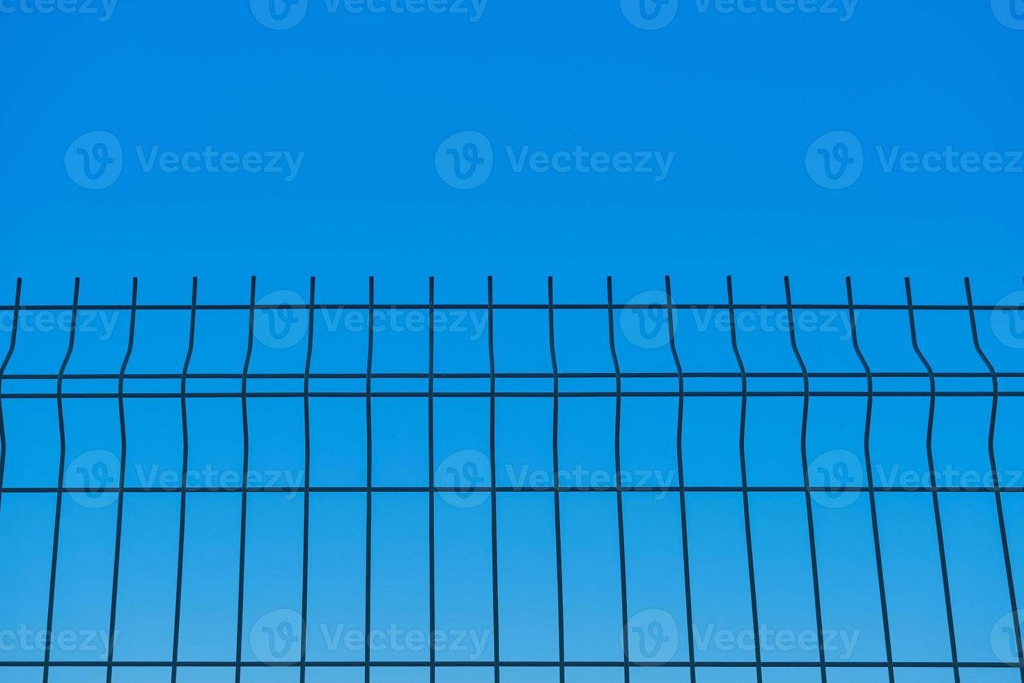 Metal fence against the background of a blue boundless sky, a blurred background, the idea of freedom and the removal of restrictions, a background for a poster or postcard photo