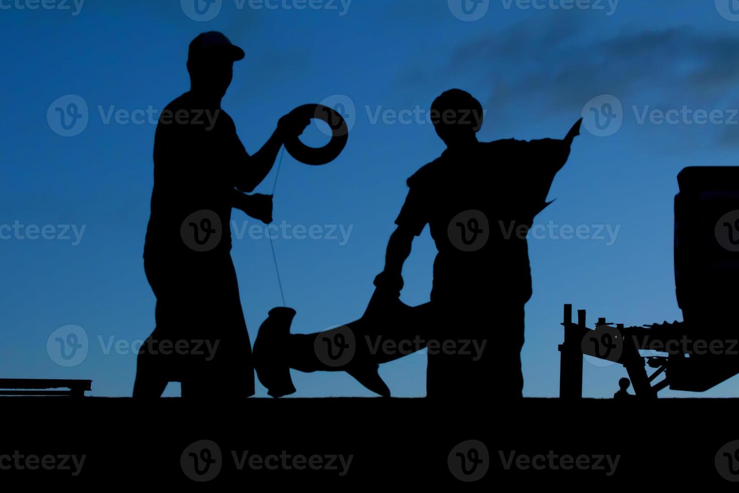 Two polynesian fisherman from Tonga before sunnrise in a silhouette with an hammerhead shark photo